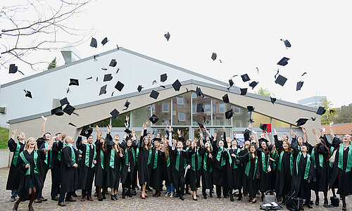 Gruppenbild von Absolventen, die ihren Hut in die Luft werfen